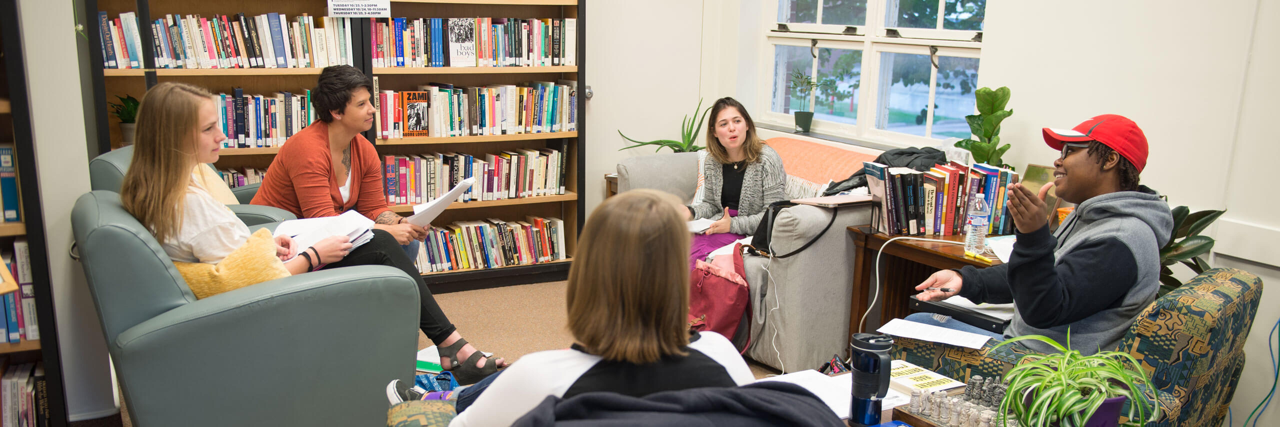 Students sit in chairs and discuss their work.