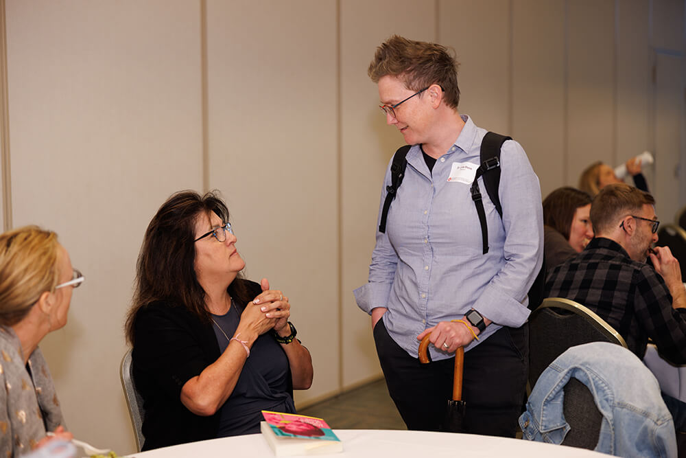 A group of people talking at a round table in an indoor setting.
